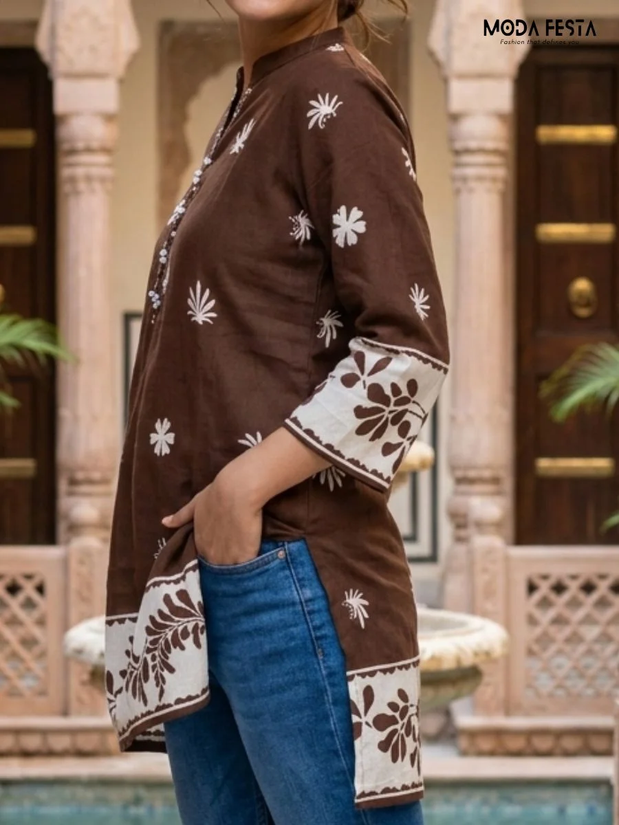 This earthy brown short kurti features a charming contrast white border and delicate floral motifs, elegantly finished with a classic mandarin collar.