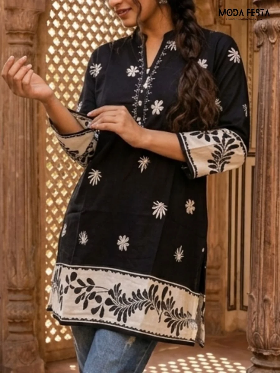 This elegant black short kurti features delicate white floral embroidery and a contrasting hemline, perfect for a chic ethnic-inspired look.