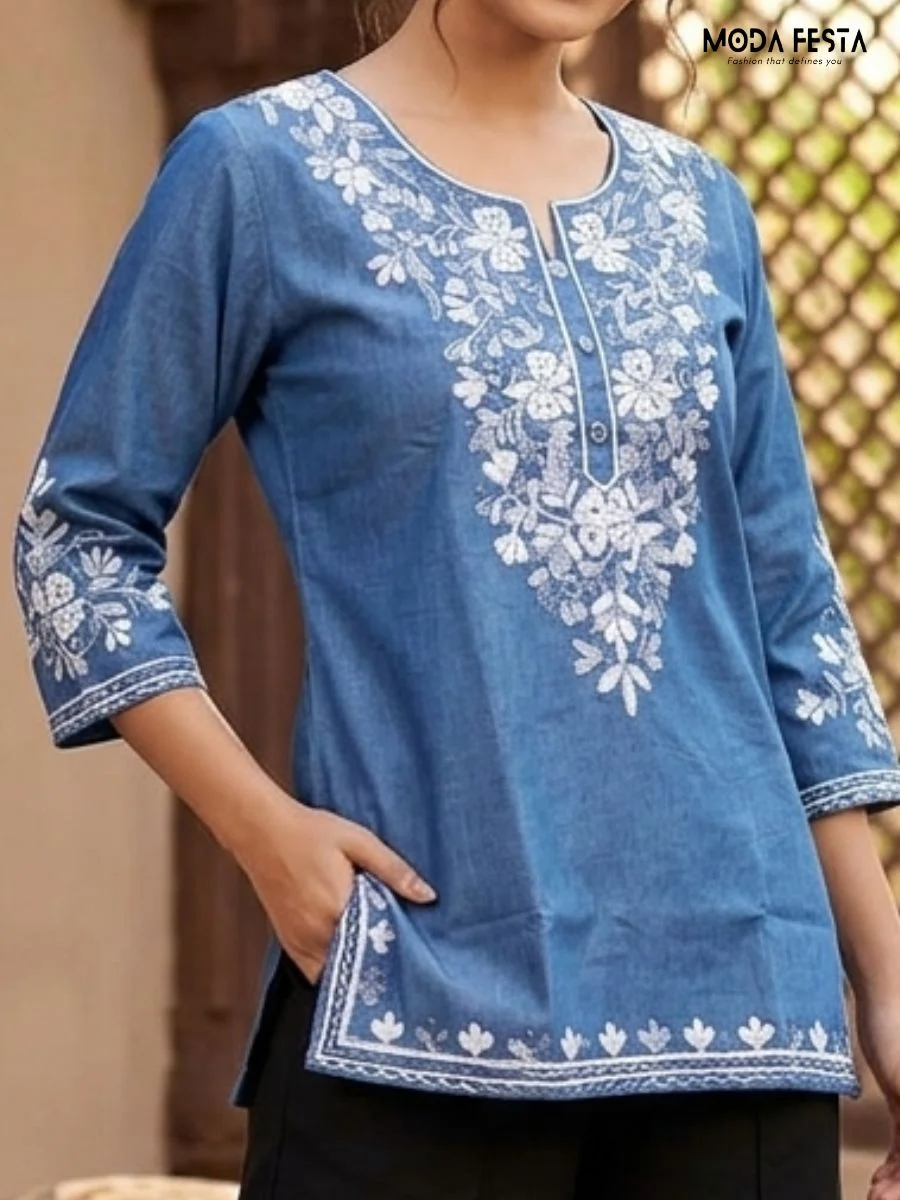 This stylish blue denim short kurti features intricate white embroidery and convenient front pockets, offering a perfect blend of comfort and ethnic charm for any casual occasion.