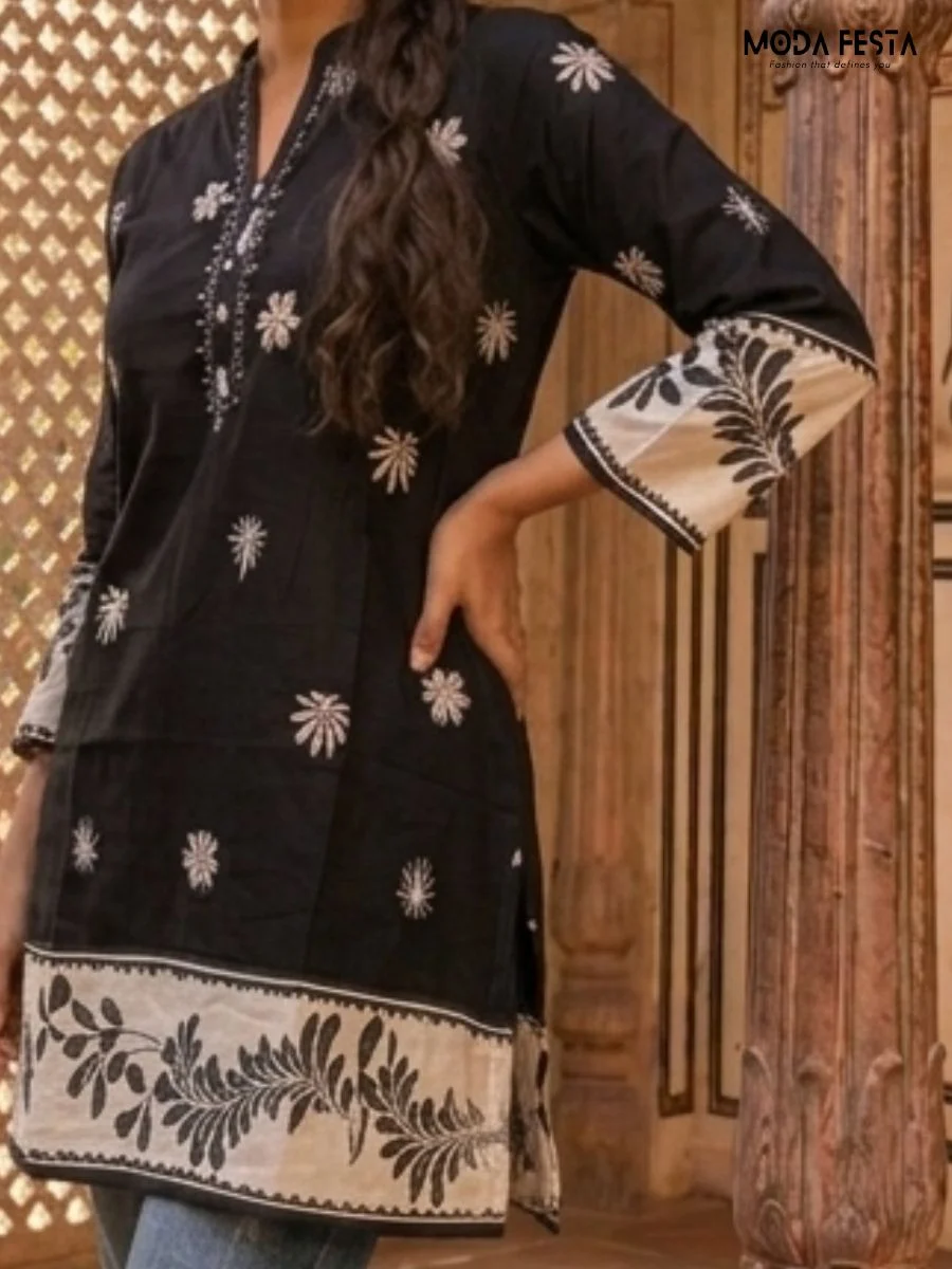 This elegant black short kurti features delicate white floral embroidery and a contrasting hemline, perfect for a chic ethnic-inspired look.